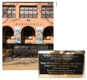 Metal bench in front of building with side image of bronze plaque dedication