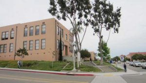 Exterior building corner with person walking on the sidewalk.